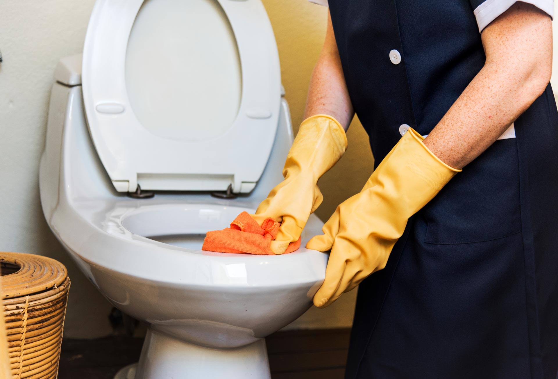Une personne portant des gants jaunes nettoie les toilettes
